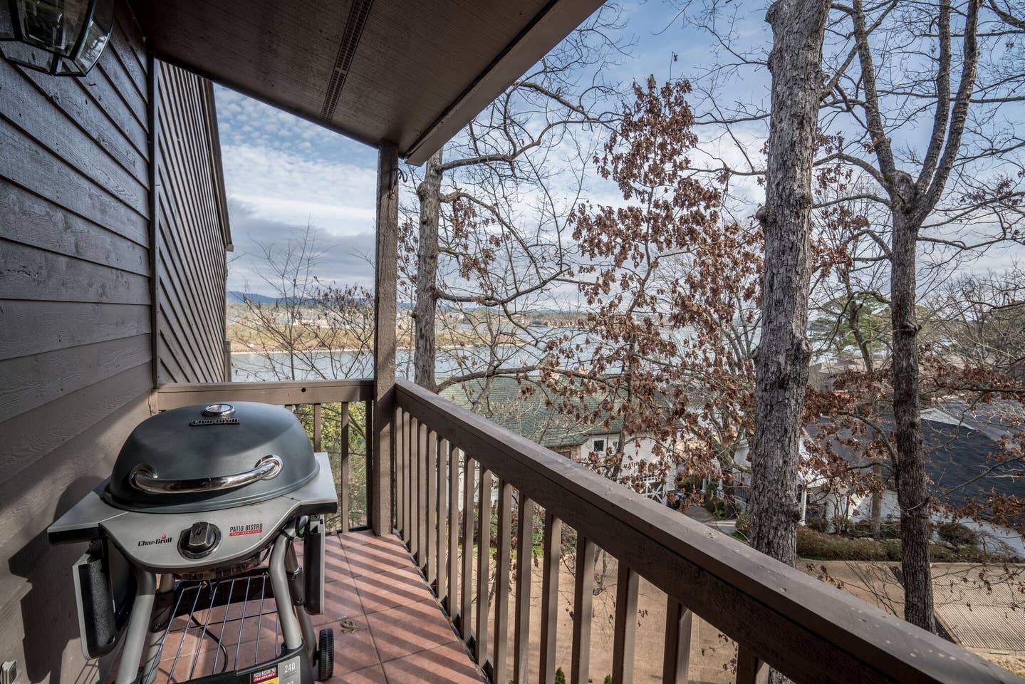 A grill is sitting on a balcony overlooking a lake.