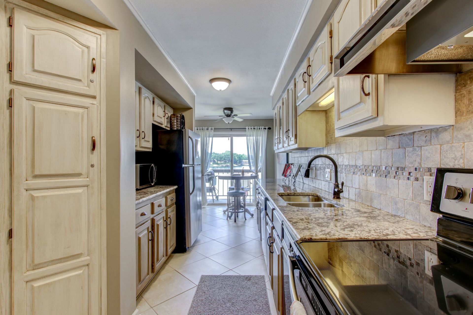 A kitchen with a stove , sink , refrigerator and cabinets.