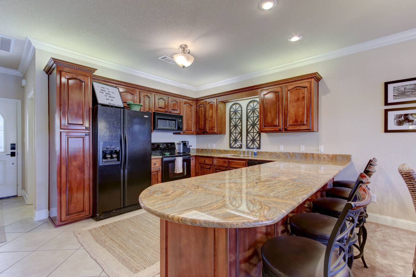 A kitchen with wooden cabinets , granite counter tops , a refrigerator , stove and microwave.