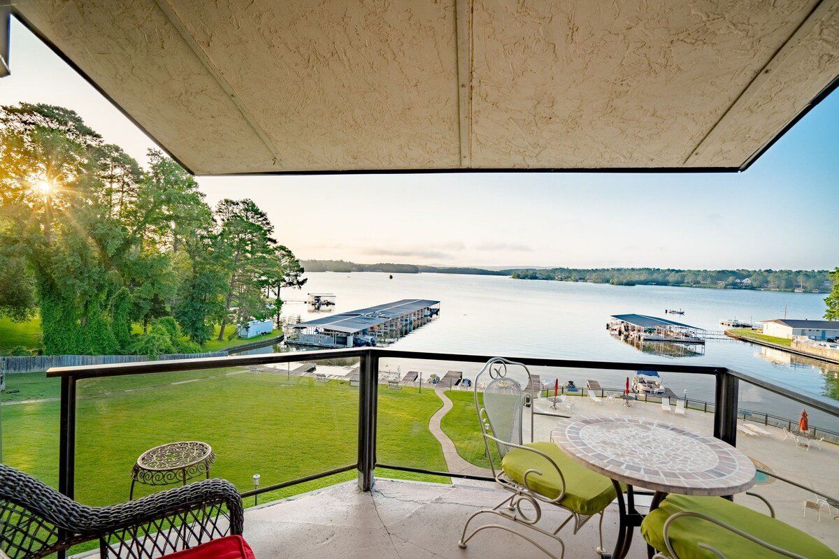 A balcony overlooking a lake with a table and chairs.