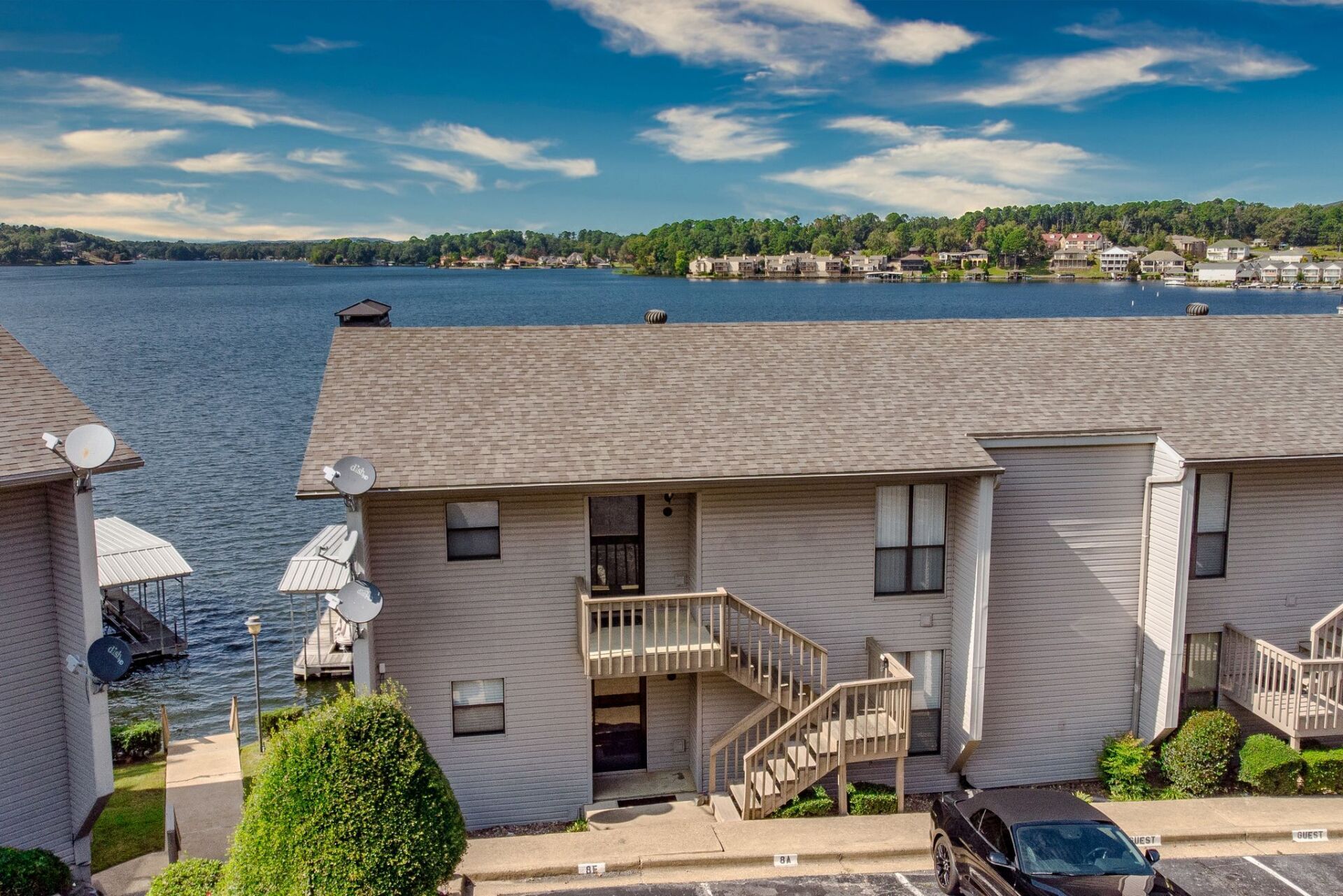 A house with stairs leading up to a balcony overlooking a body of water.