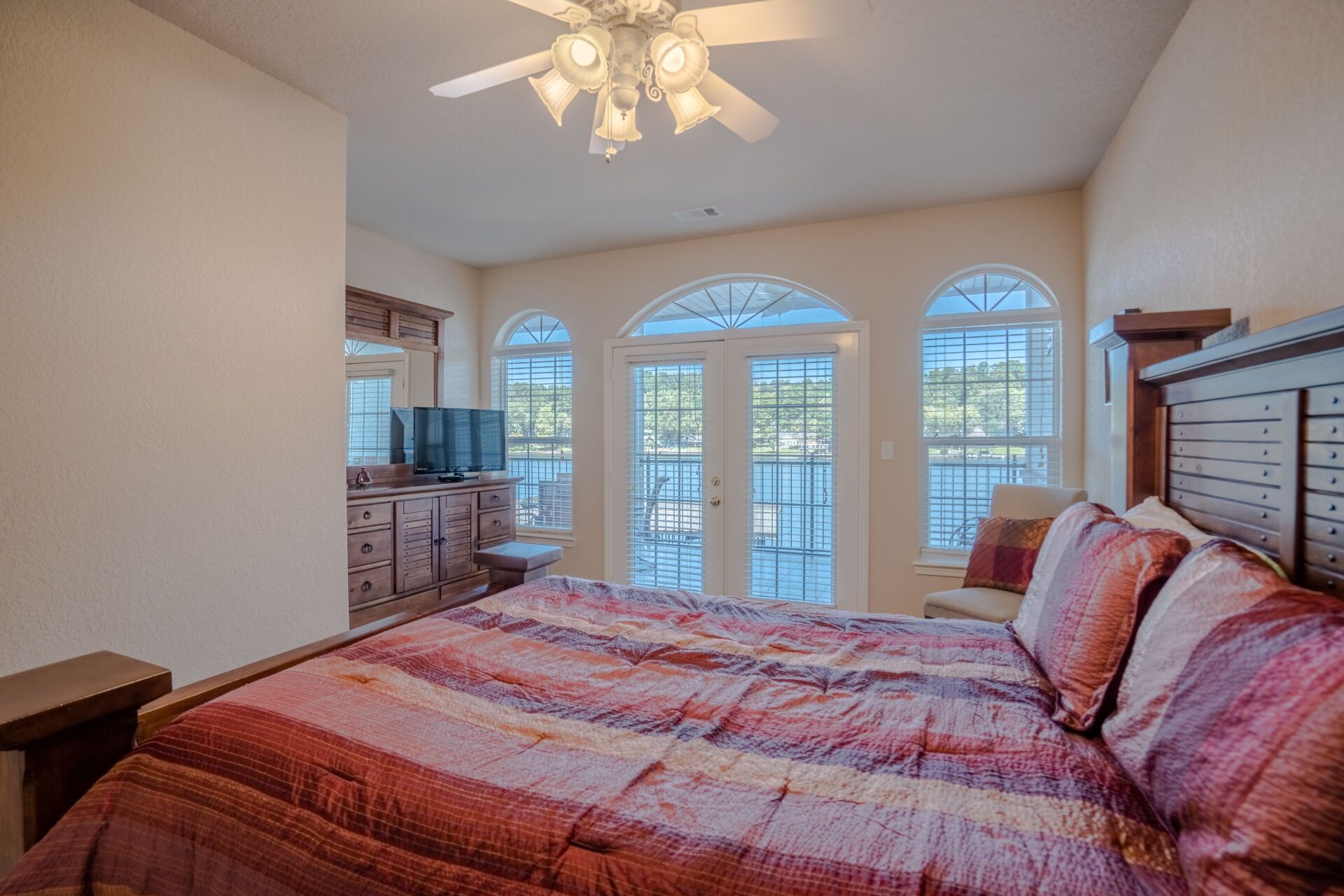 A bedroom with a king size bed and a ceiling fan.