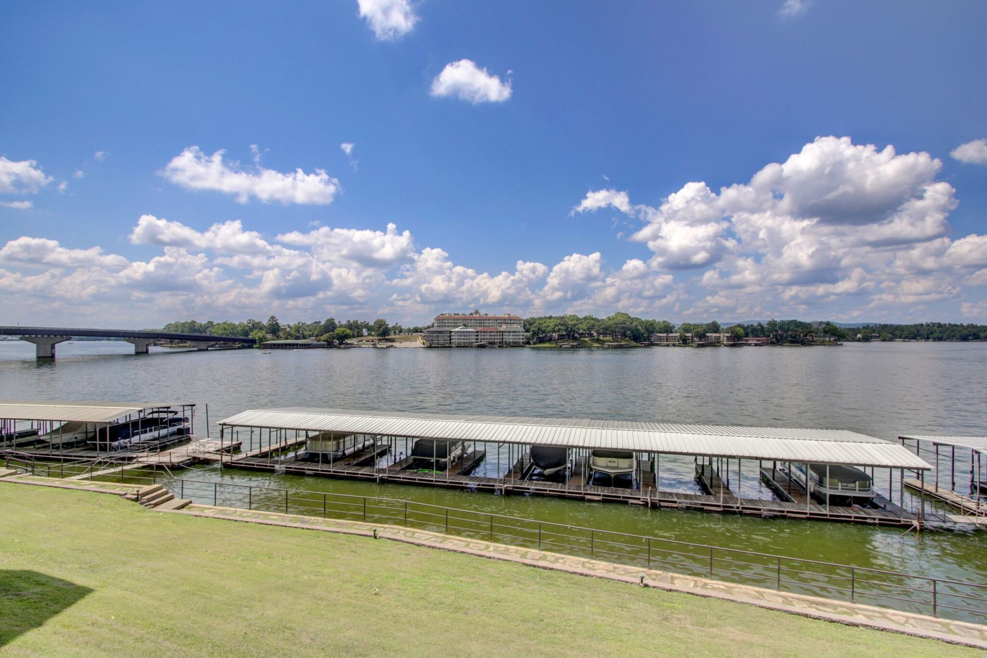 A row of boats are docked at a marina on a lake.