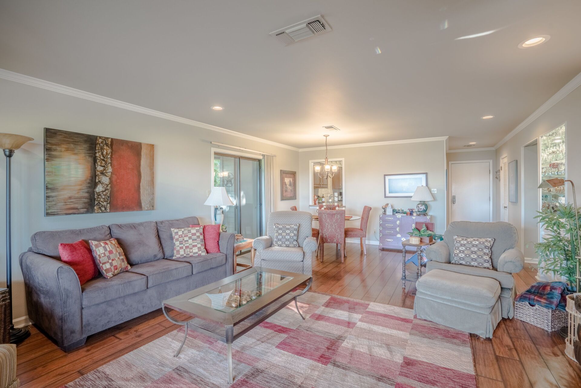 A living room with a couch , chairs , a coffee table and a rug.