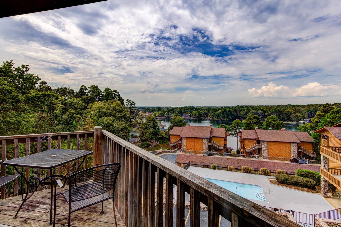 A view of a lake from a balcony with a table and chairs.