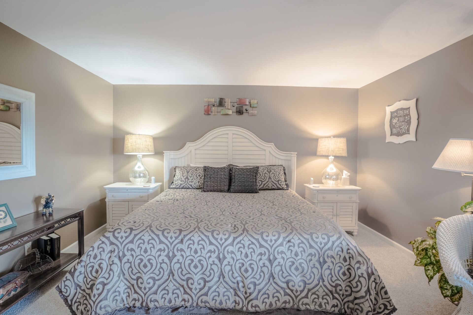 A bedroom with a king size bed , nightstands , lamps and a mirror.