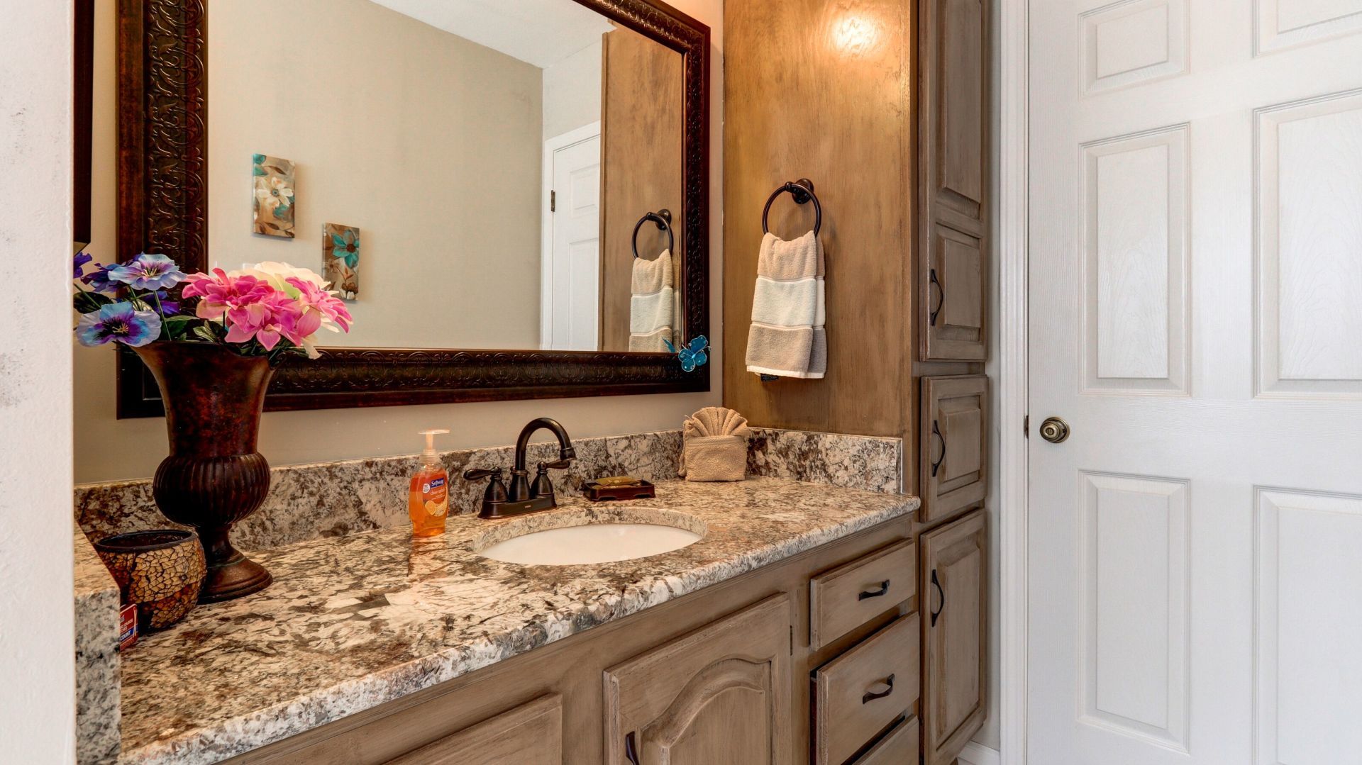 A bathroom with a sink , mirror and cabinets.