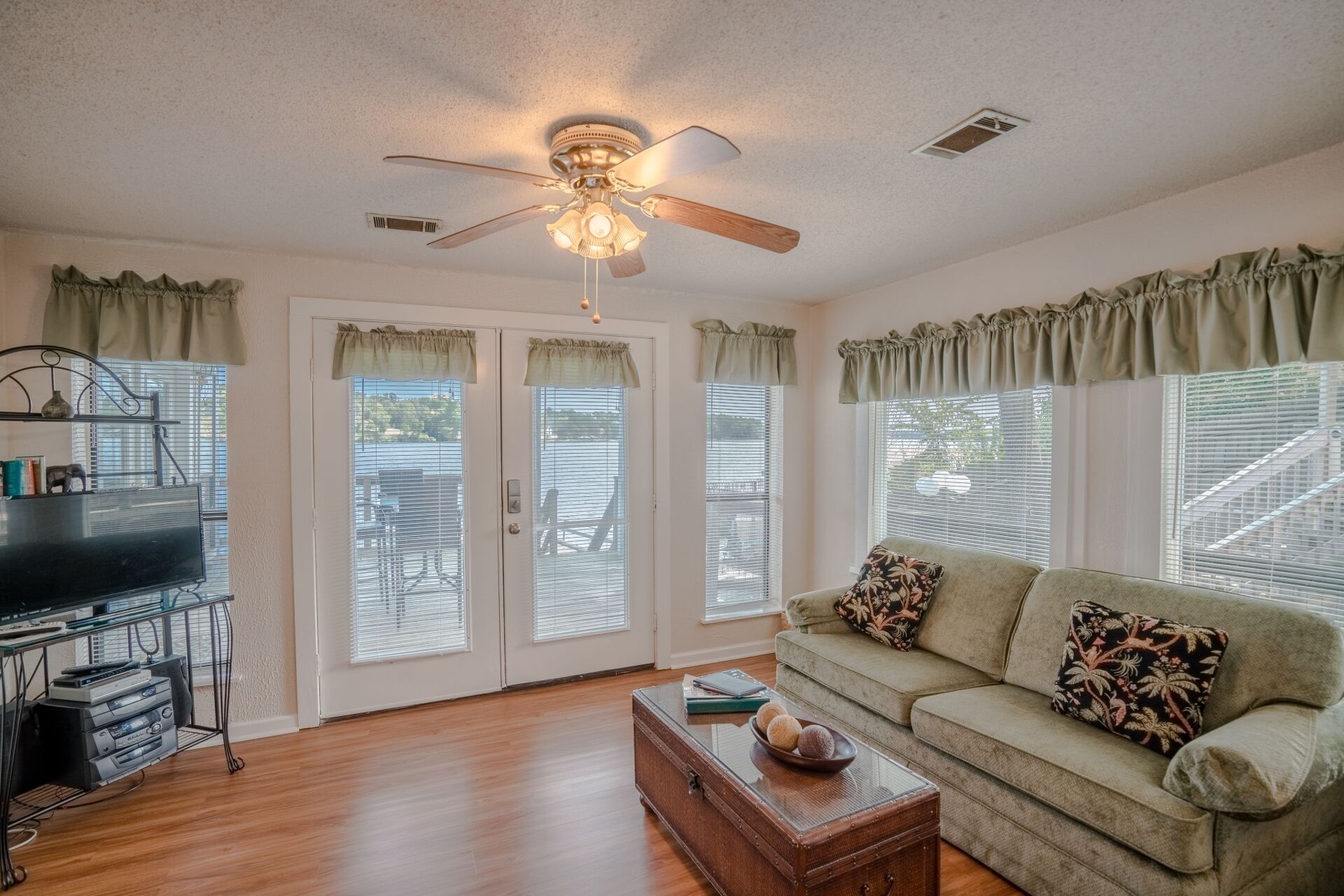 A living room with a couch , coffee table , television and ceiling fan.