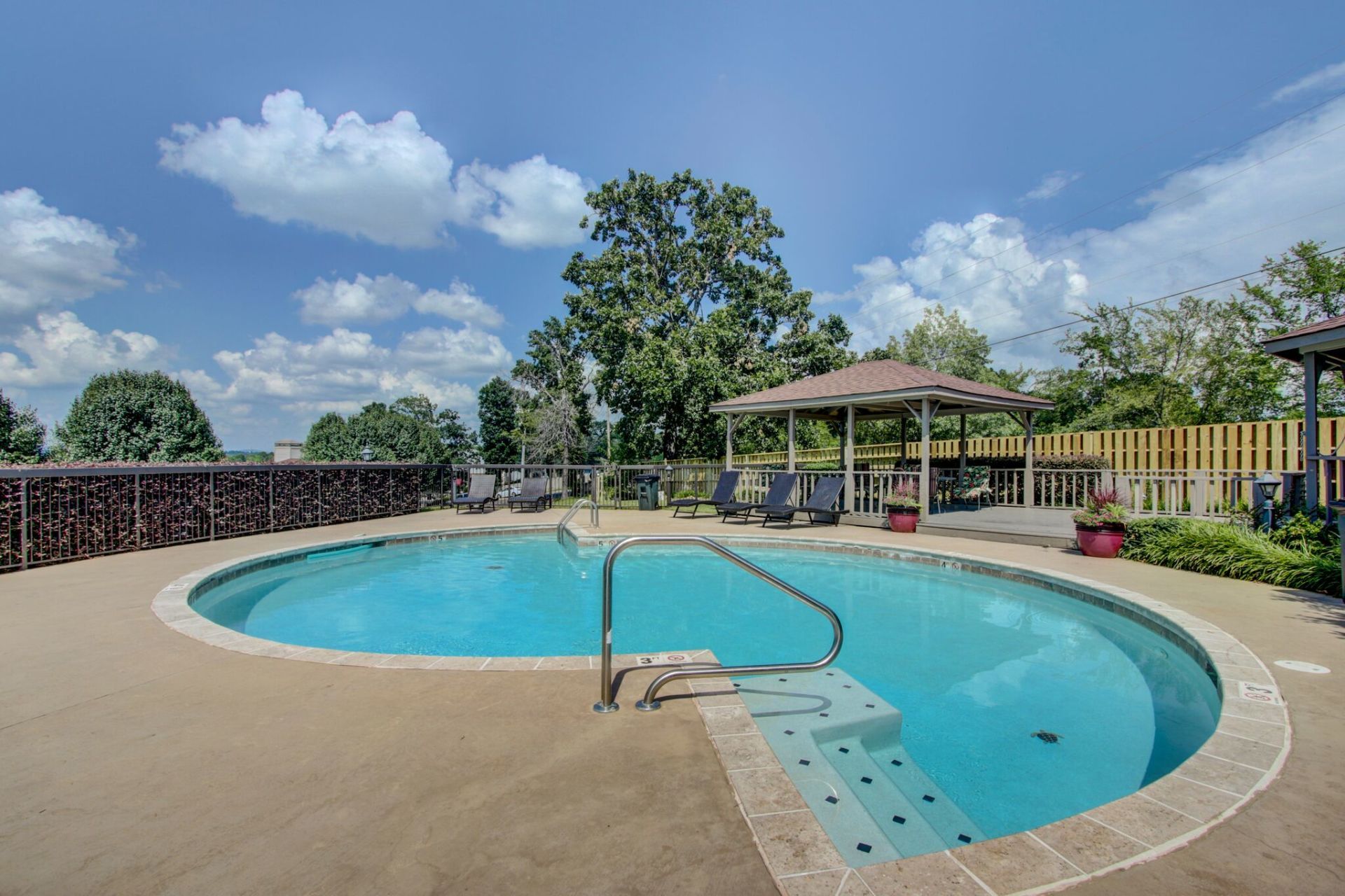 There is a large swimming pool with a gazebo in the background.