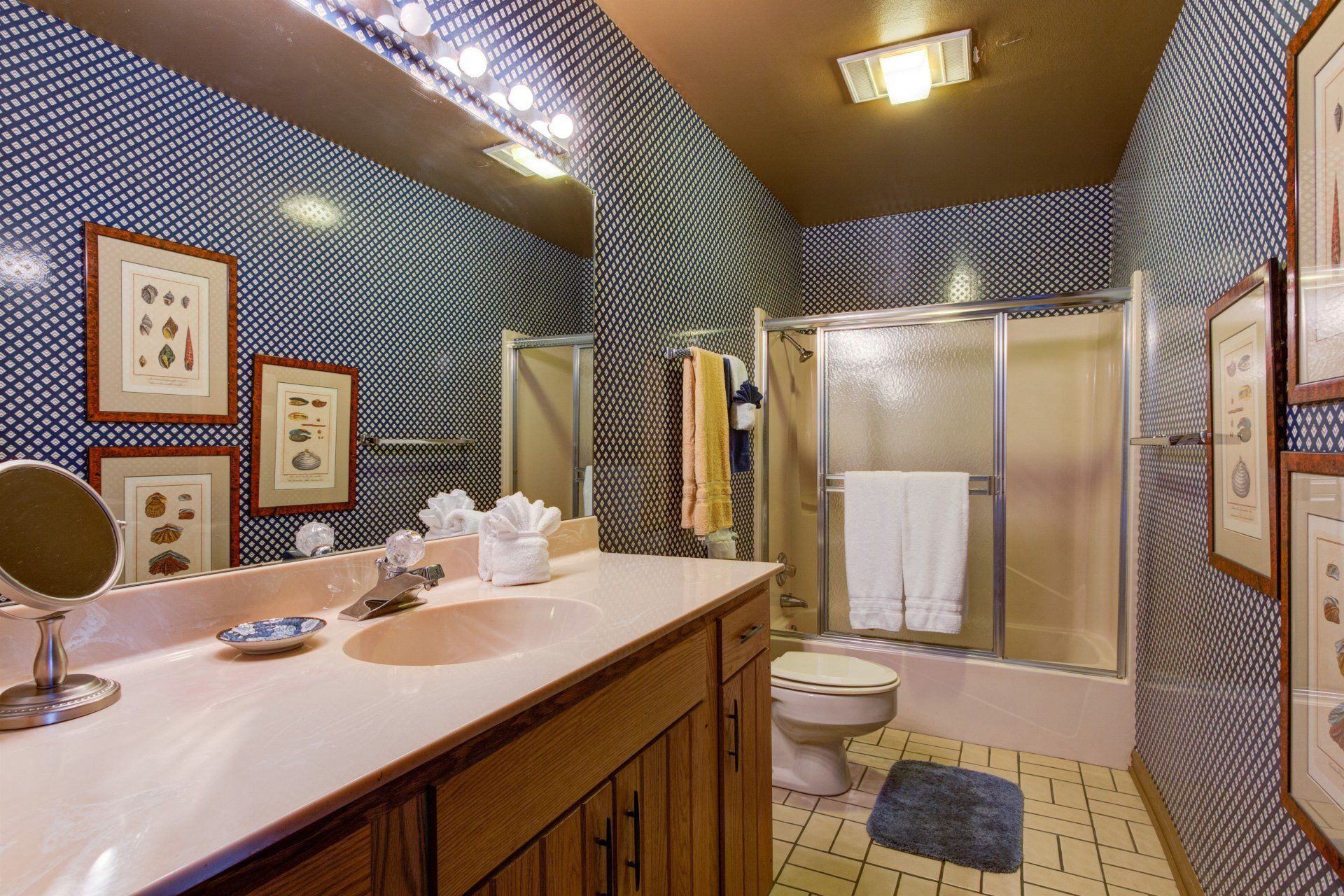 A bathroom with a toilet , sink , mirror and shower.