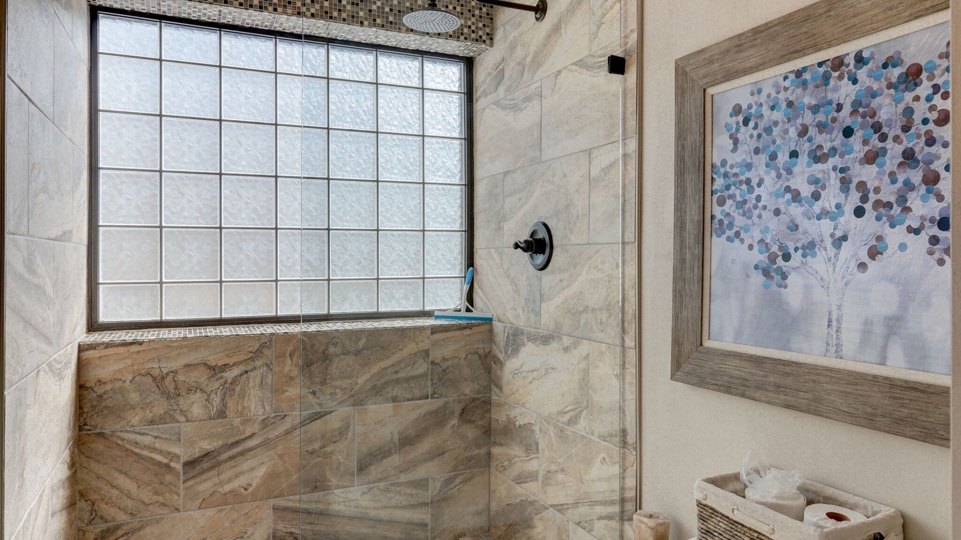 A bathroom with a walk in shower and a picture on the wall.