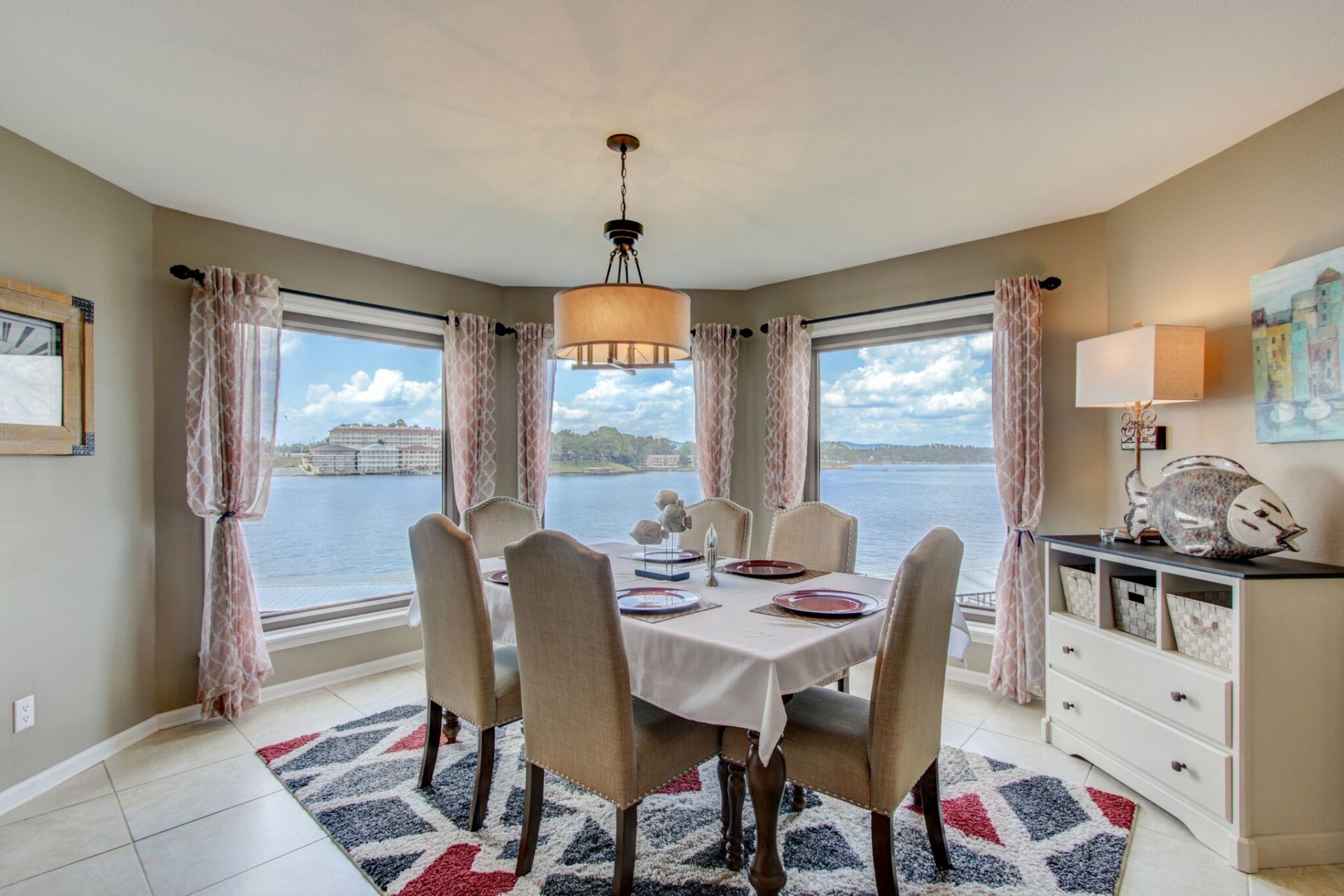 A dining room with a table and chairs and a view of the water.