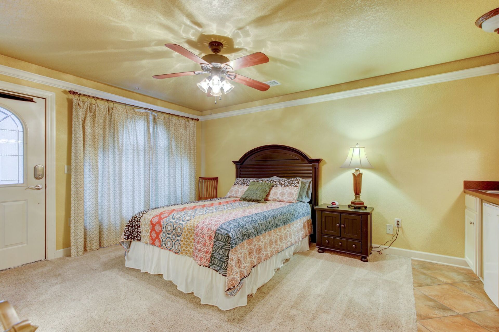 A bedroom with a bed , nightstand , lamp and ceiling fan.