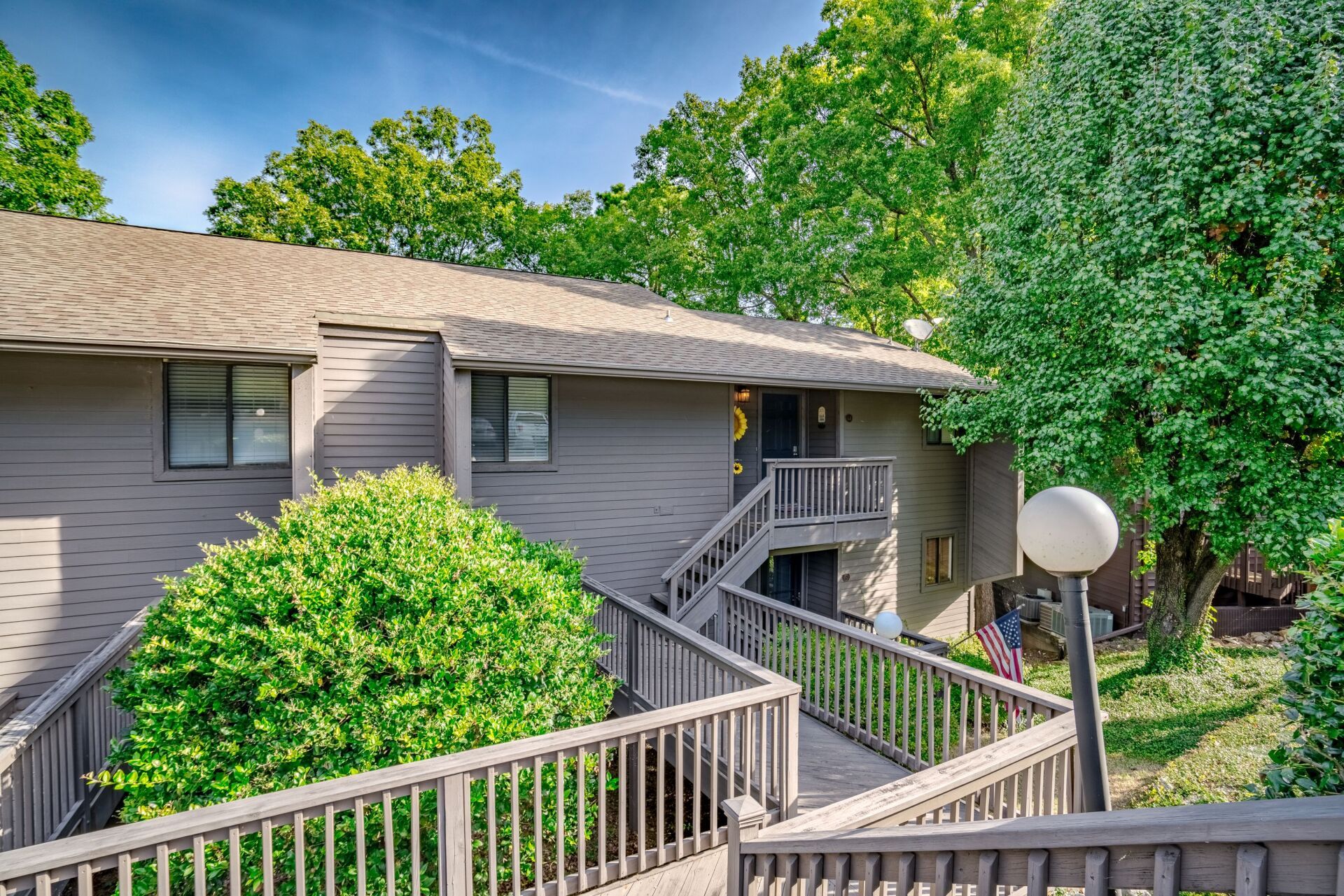 A house with stairs leading up to it and trees in front of it.