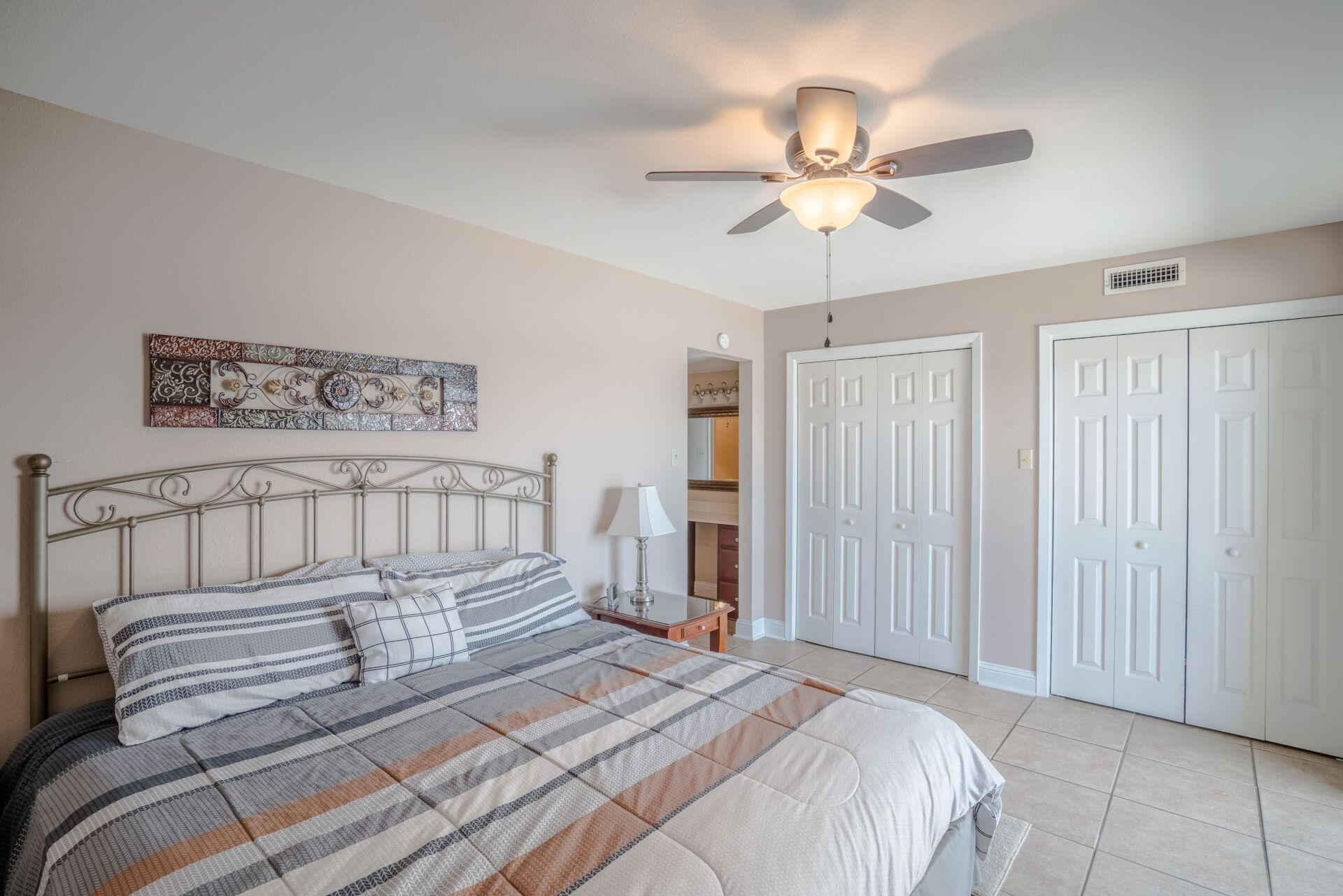 A bedroom with a king size bed and a ceiling fan.