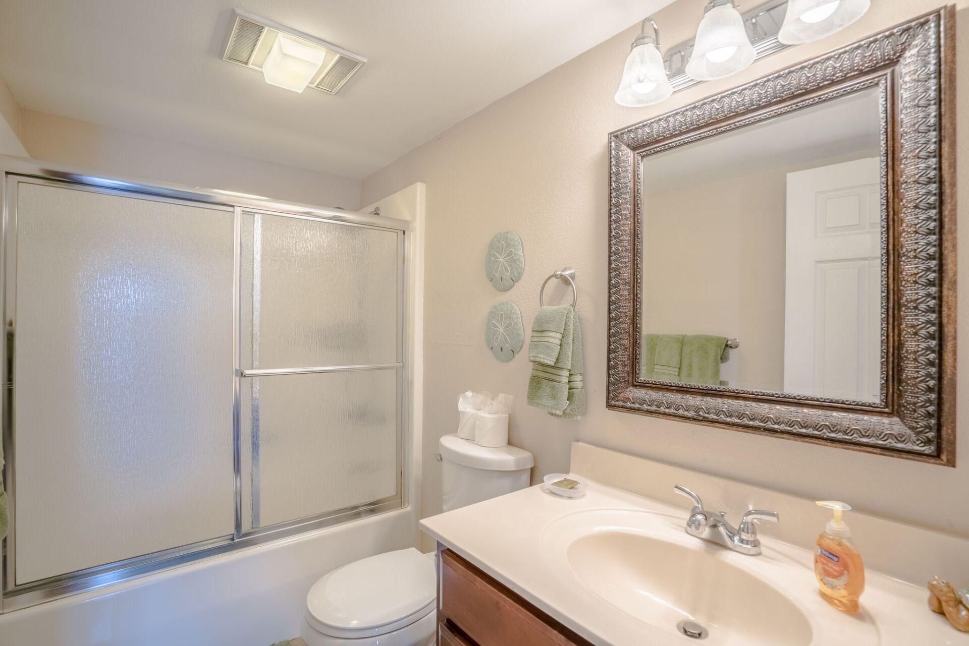 A bathroom with a sink , toilet , shower and mirror.
