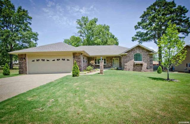 A house with a large lawn and trees in front of it.