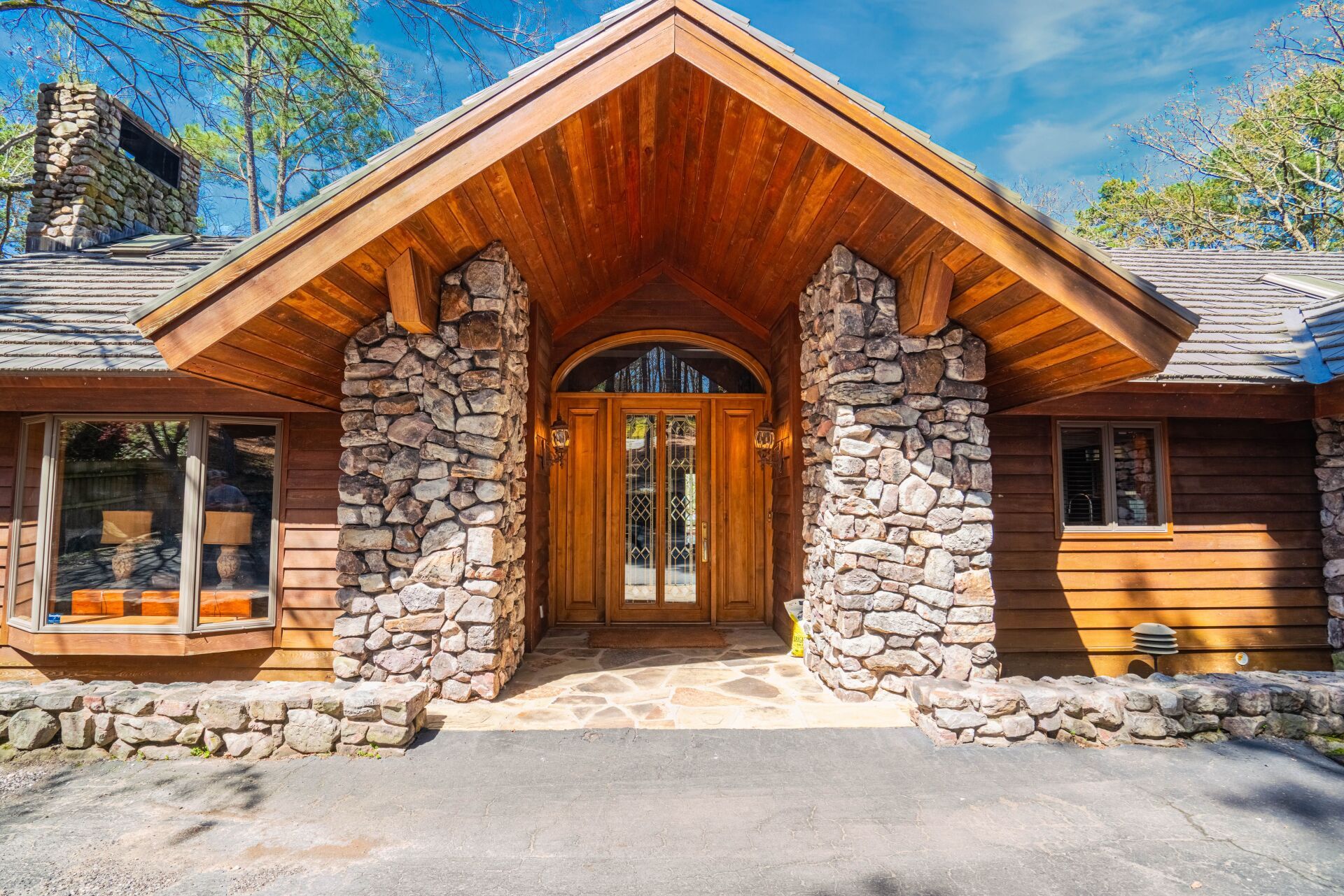 The front of a wooden house with a stone wall and a wooden roof.