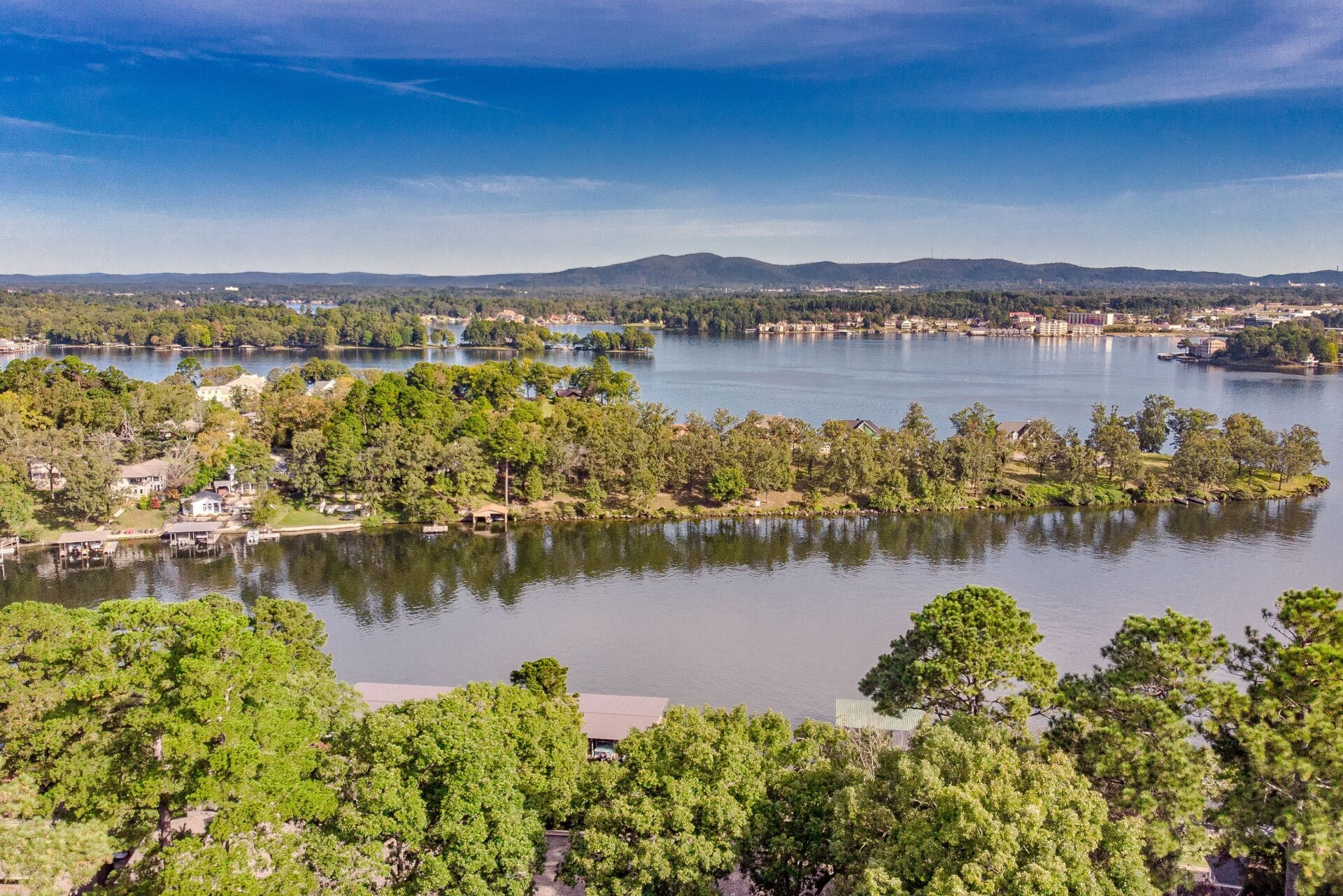 An aerial view of a lake surrounded by trees on a sunny day.