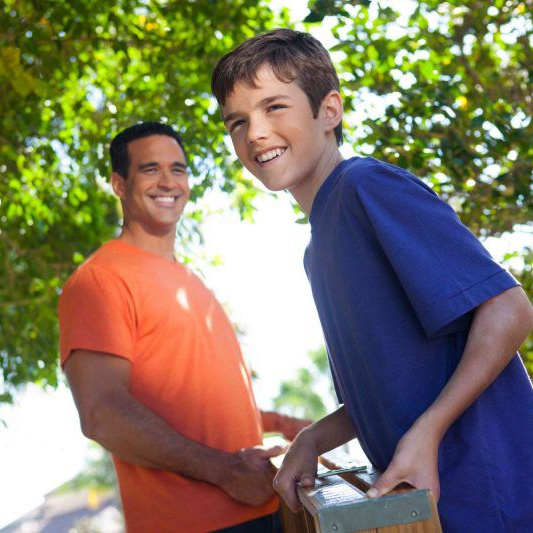 boy in blue shirt standing next to man in orange shirt for client testimonial