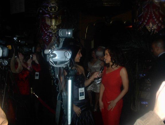 A woman in a red dress is being interviewed by a cameraman