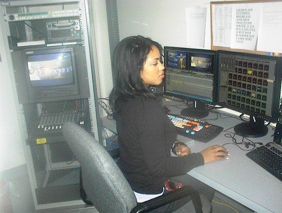 A woman sits at a desk in front of two monitors