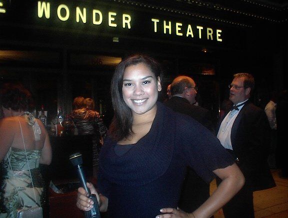 A woman stands in front of a wonder theatre sign