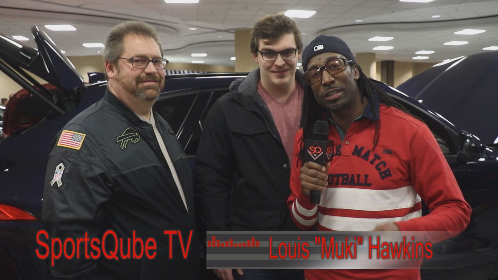 Three men are posing for a picture in front of a car.