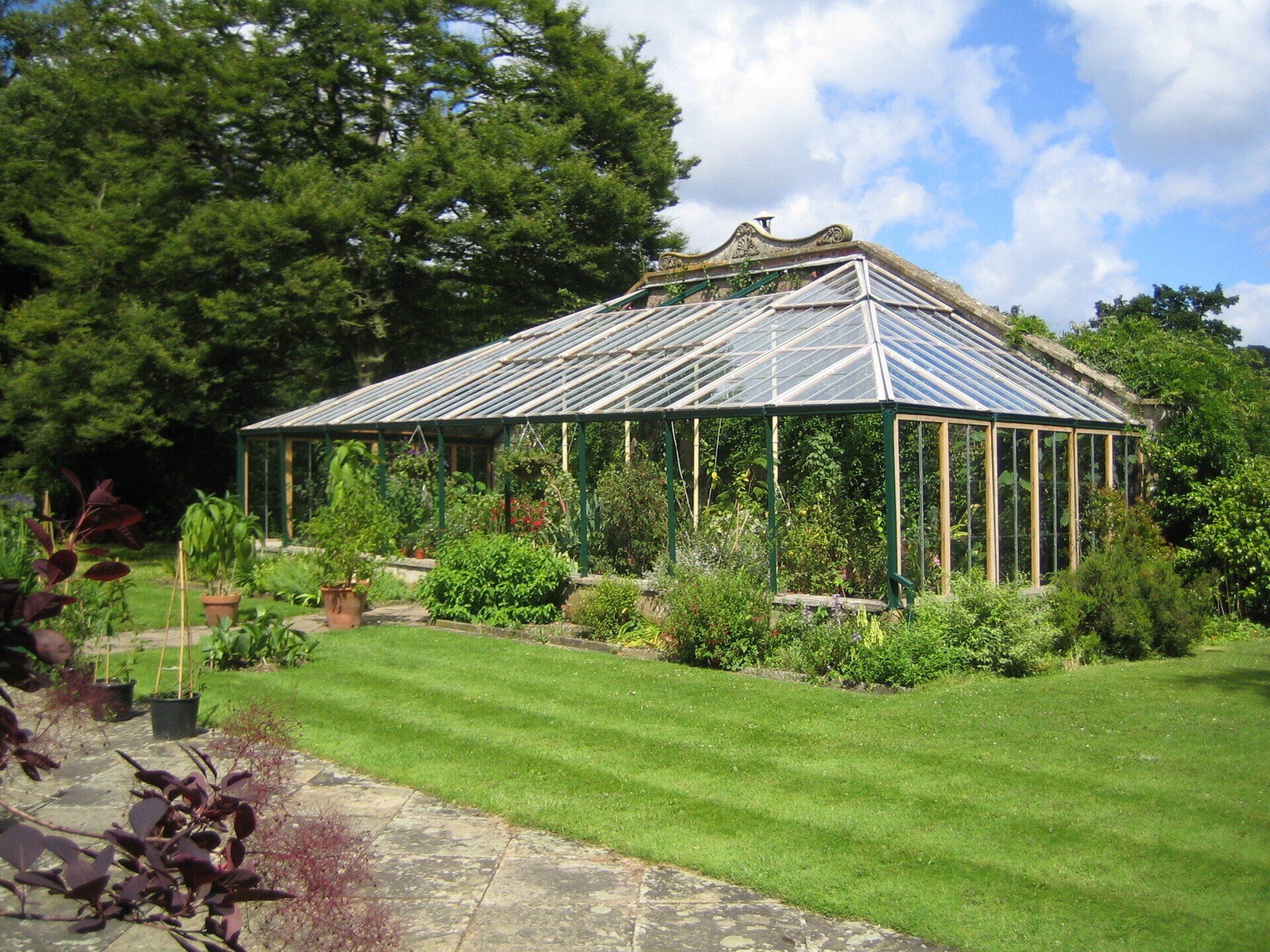 A large greenhouse is surrounded by a lush green lawn