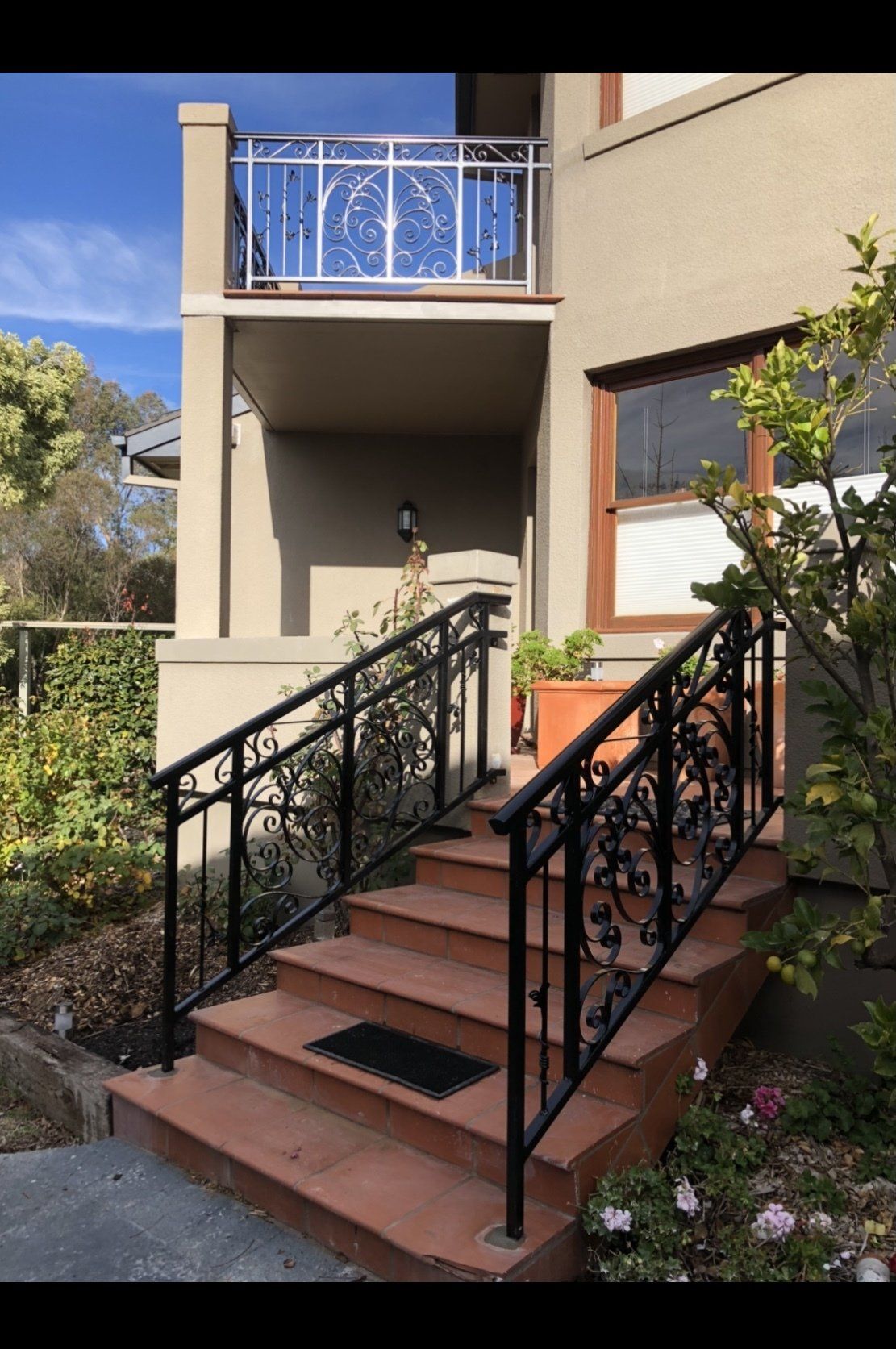 A set of stairs leading up to a balcony with a wrought iron railing.