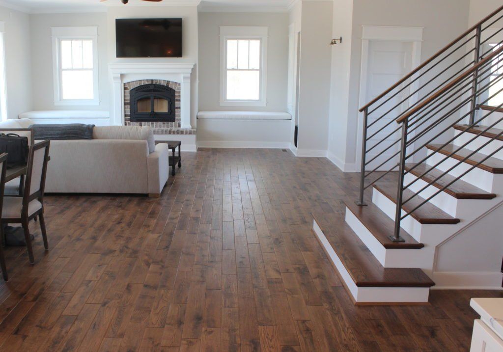 Living room with hardwood floors, fireplace, staircase with metal railing.