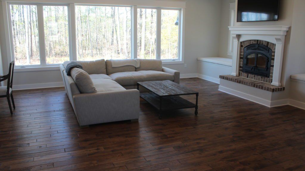 Living room with large windows, a light-colored sectional sofa, a dark coffee table, and a fireplace.