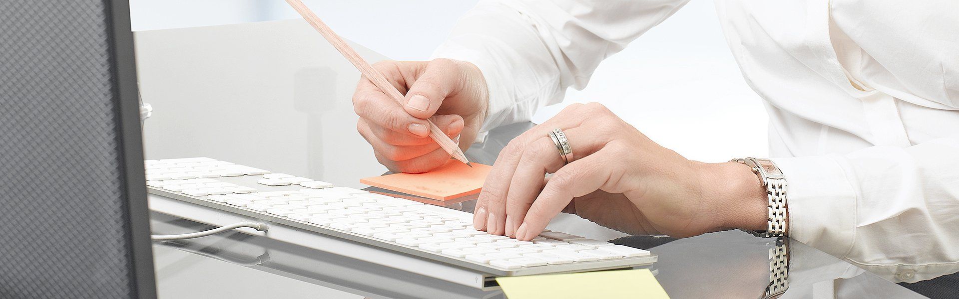 a lady using pen and stick pad while working on computer