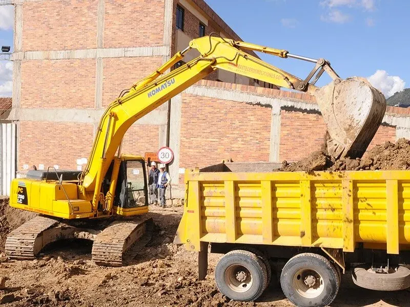 Una excavadora amarilla está cargando tierra en un camión volquete.