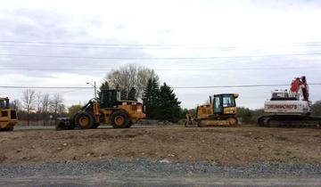 Construction equipment on a dirt lot under an overcast sky.