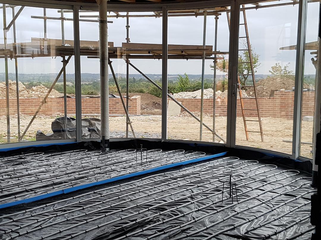 Construction site with rebar flooring, wooden scaffolding, and a view of the sea beyond.