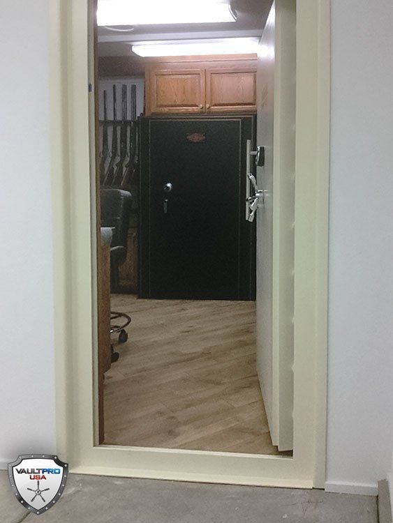 Hallway view of a kitchen with wooden cabinets, black refrigerator, and light wood flooring