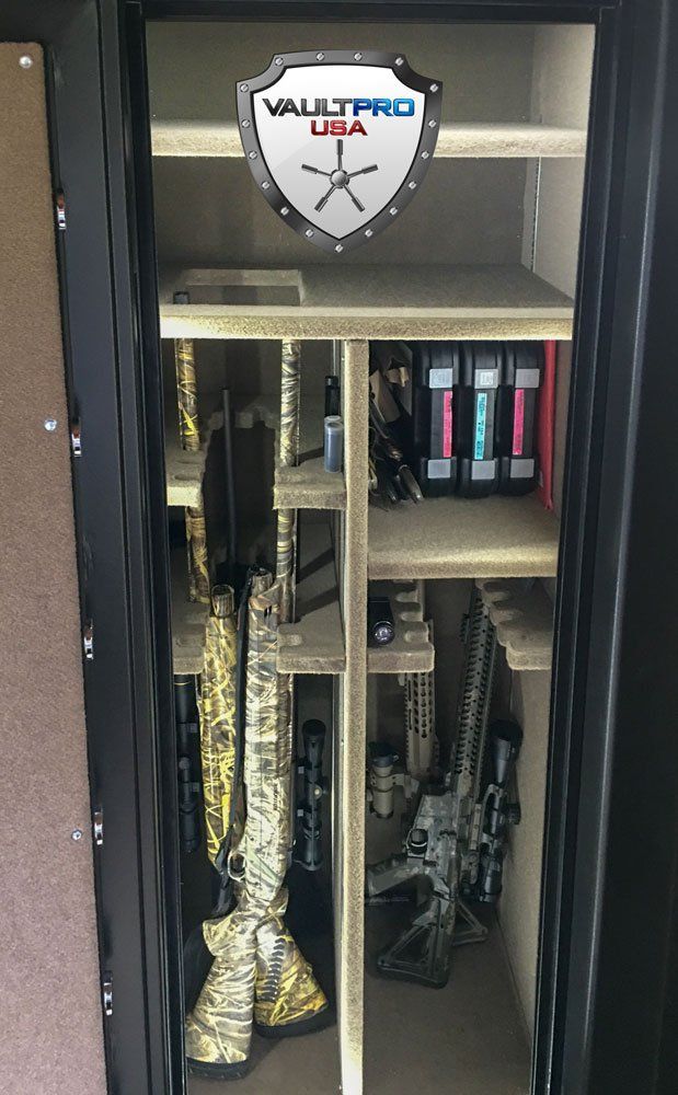 Open safe with rifles and ammunition inside, including a rifle case and camouflage gun covers.