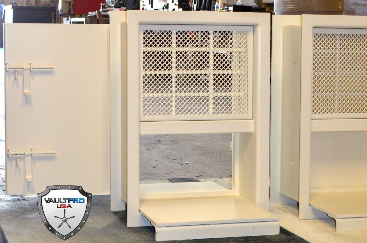 Two beige metal cabinets with mesh-front openings in a workshop or storage area