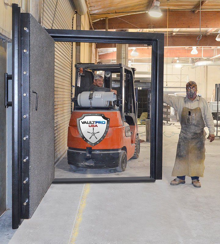 Forklift entering a warehouse through a black gate, with a worker in a dusty apron standing nearby.