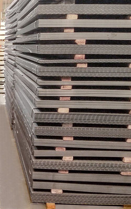 Stacked metal sheets in a warehouse, viewed from the side.