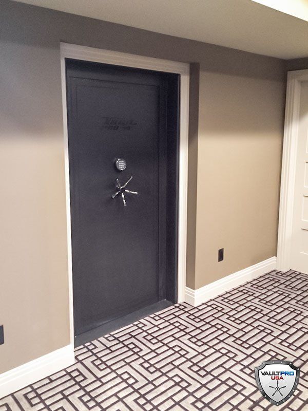 Dark blue vault-style door in a beige hallway with patterned carpet.