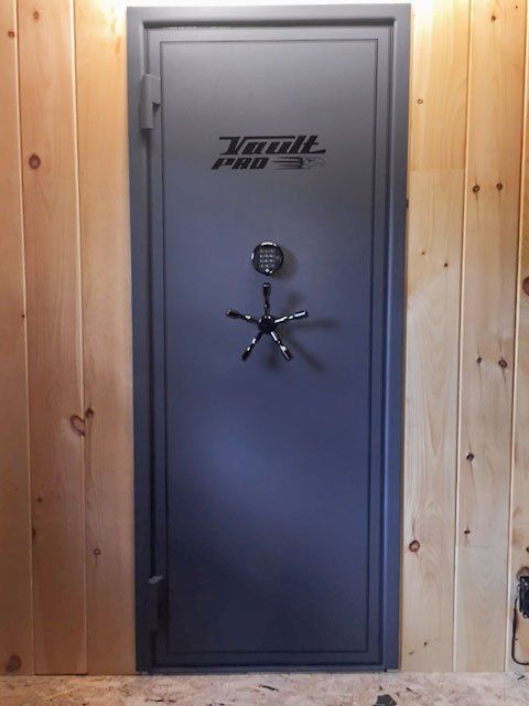 Gray secure vault door with combination lock in a wooden-paneled room