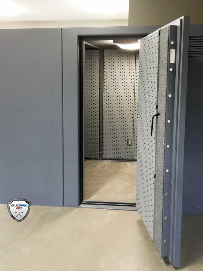 Open vault door revealing a gray, perforated security room inside a concrete enclosure.