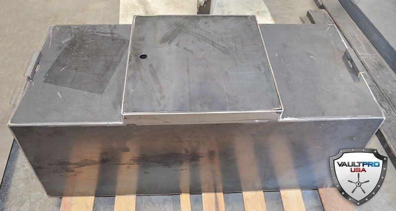 Metallic rectangular platform with a raised center panel, shown on a pallet in a workshop.