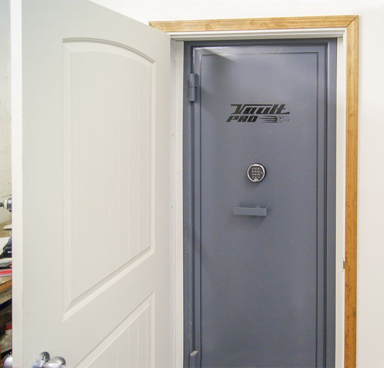 Open white door revealing a gray walk-in safe with a round lock and handle