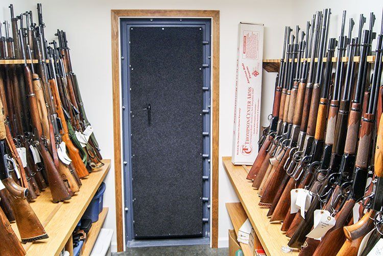 Gun rack storage room with rifles lined on shelves on both sides of a central door