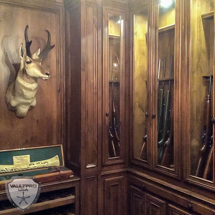 Wood-paneled room with a mounted deer head, mirrored cabinets, and a small table with a sign.