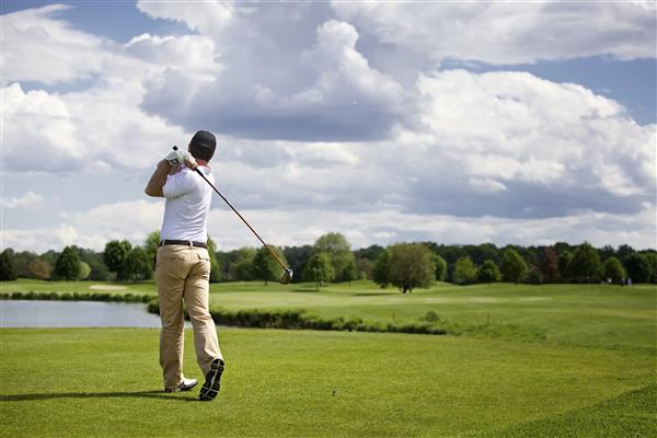 A man is swinging a golf club on a golf course.