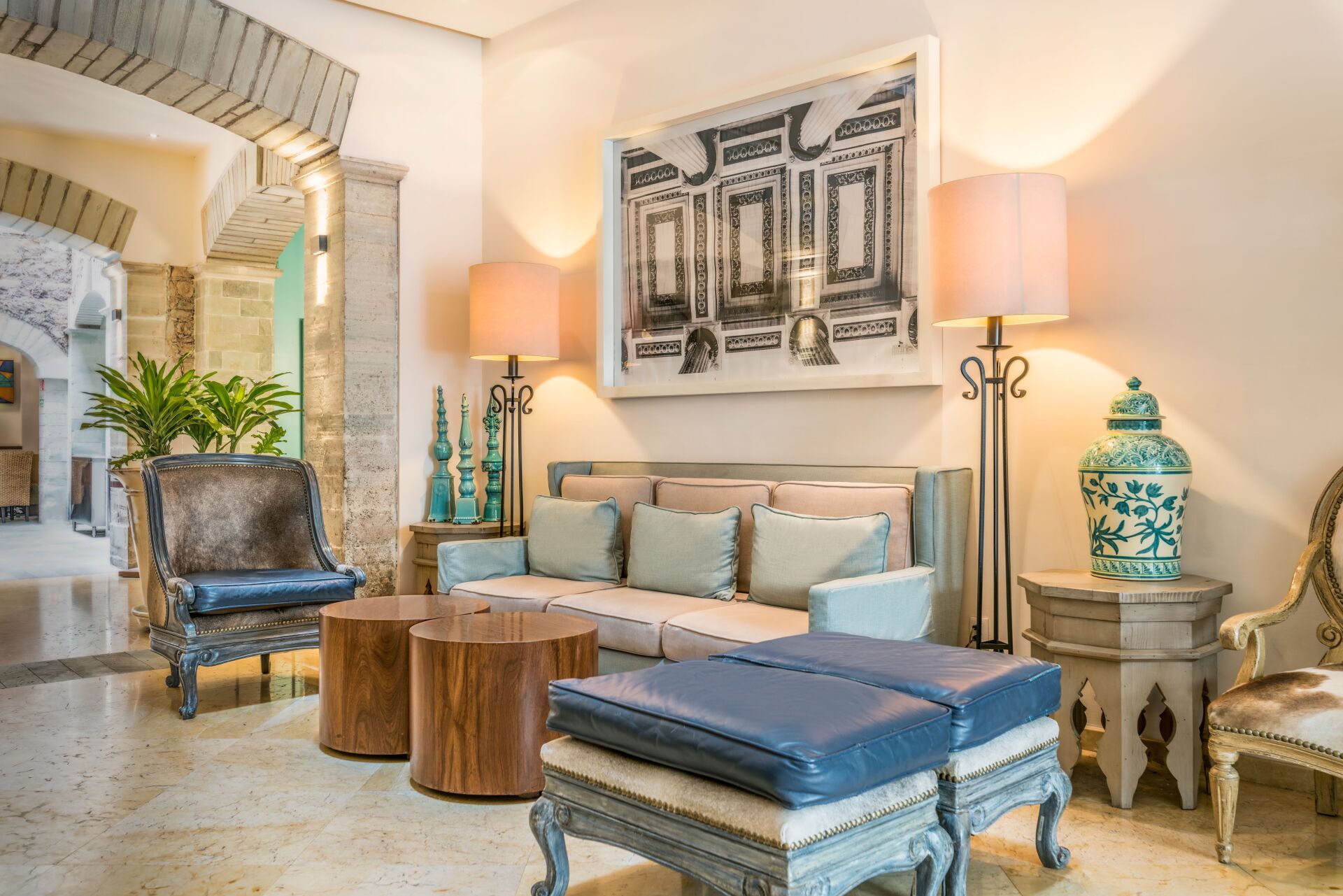Elegant living room with turquoise accents, carved stools, a sofa, lamps, and ornate decor